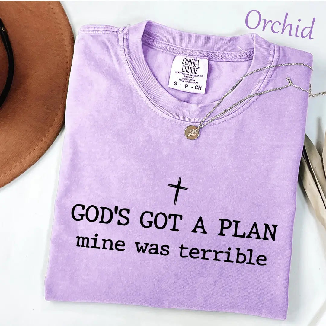 Folded Orchid lavender Comfort Colors tee with a black cross and god's got a plan, mine was terrible lettering