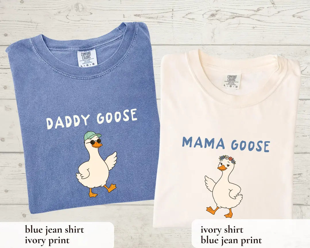 Folded adult Daddy Goose Blue Jean and Mama Goose Ivory T-shirts, with complementary printed goose designs.