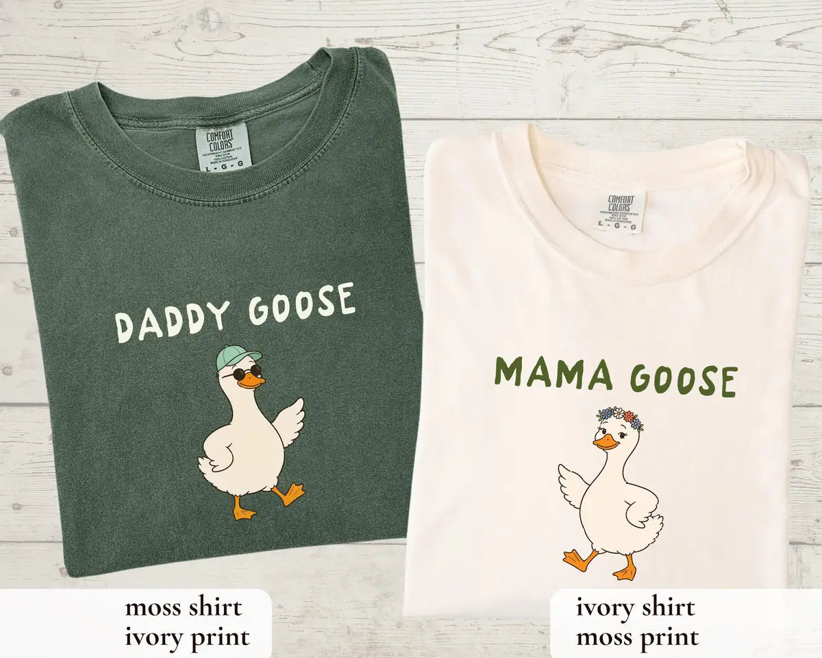 Folded adult Mama Goose Ivory and Daddy Goose Moss T-shirts with matching birthday goose artwork.