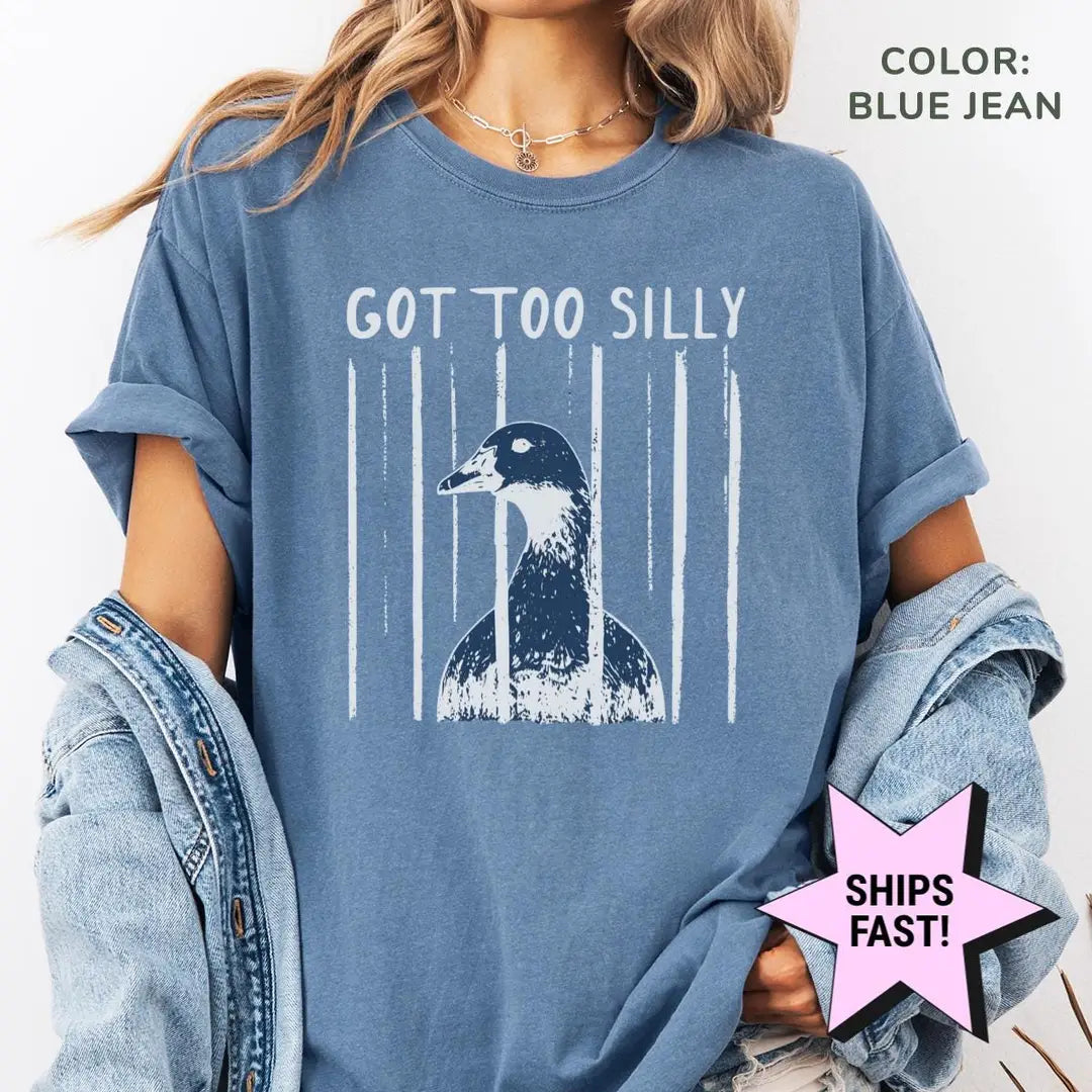 Woman in a Blue Jean Comfort Colors tee and a denim jacket with got too silly above a goose head and white brush stripes