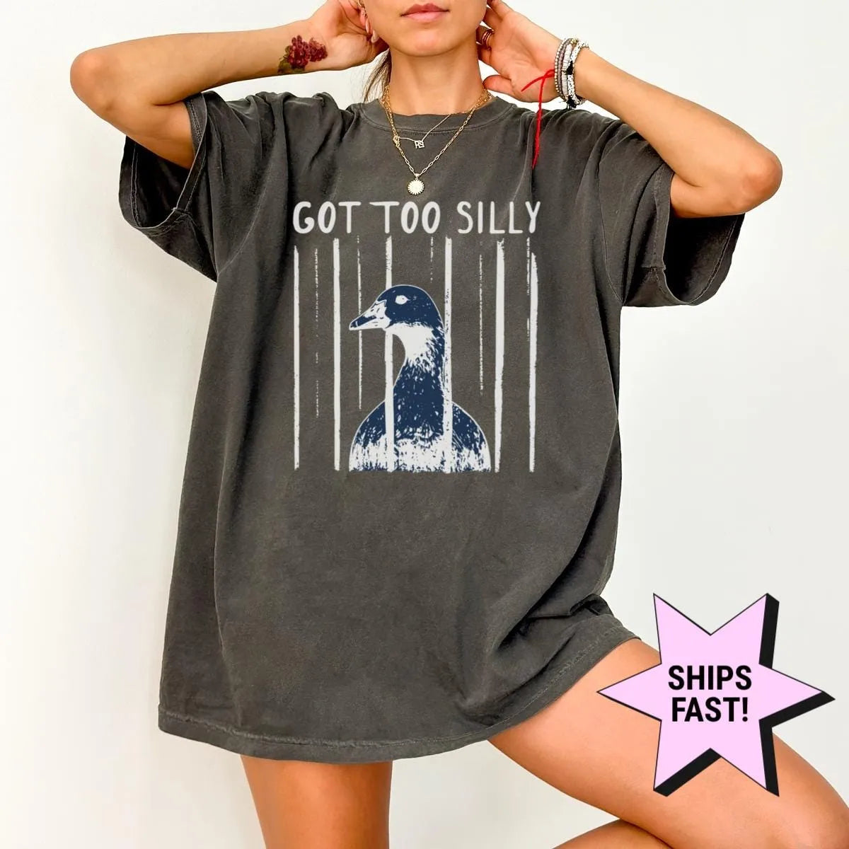 Woman in a Pepper Comfort Colors tee, hands behind her head, with got too silly and a goose head between white stripes