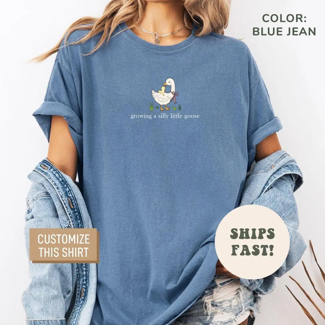 Woman in a Blue Jean Comfort Colors tee and a denim jacket with a tiny goose and ducklings above the caption