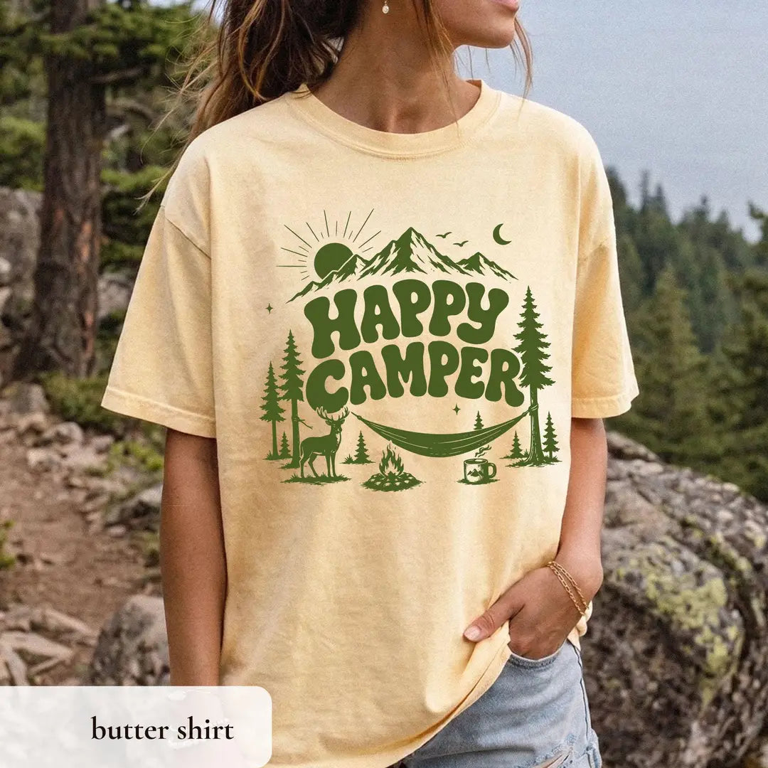Woman in a Butter yellow Comfort Colors tee on a rocky ledge, green happy camper lettering, deer, hammock and mug