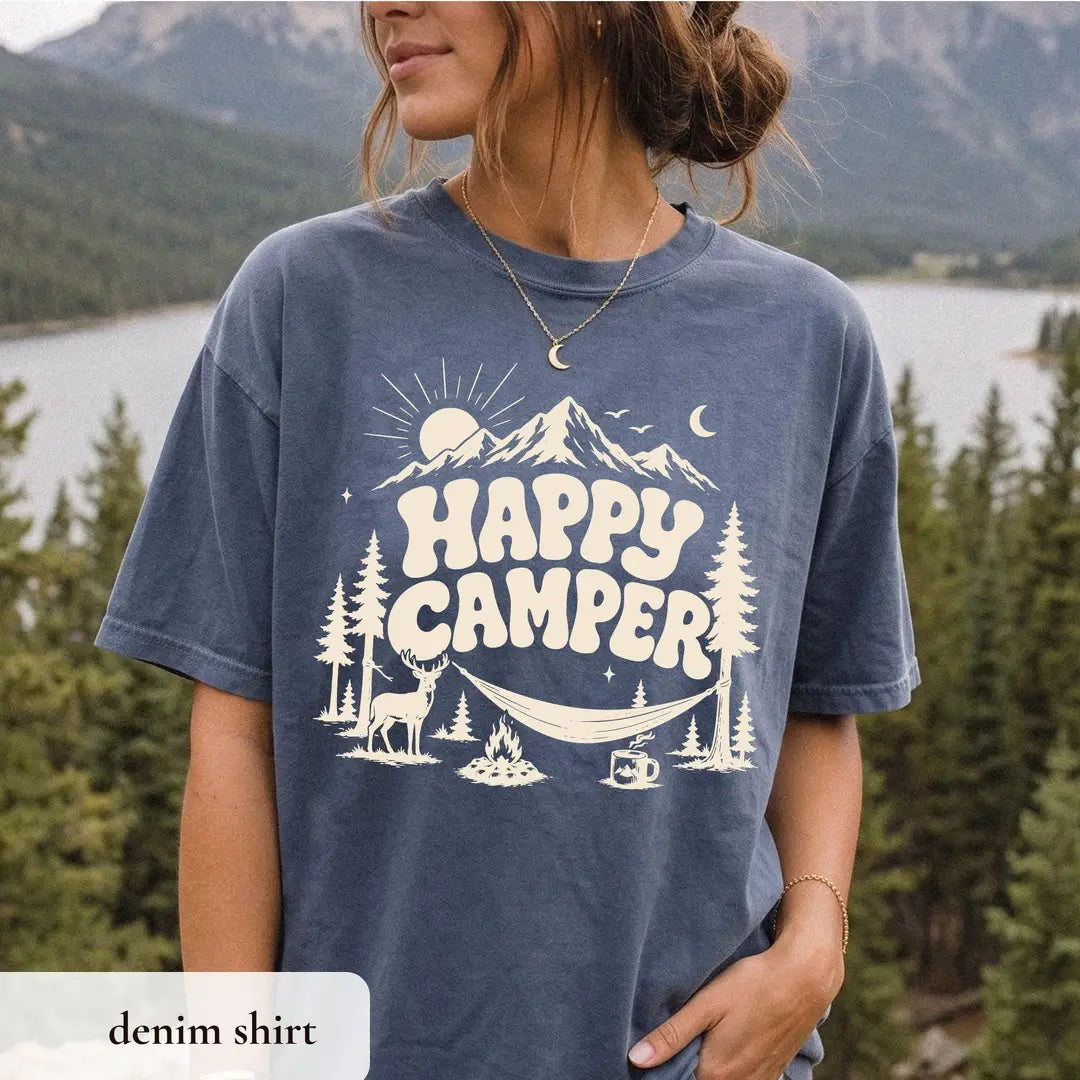 Woman in a Denim Comfort Colors tee by a lake, ivory happy camper under a mountain with deer, hammock and mug