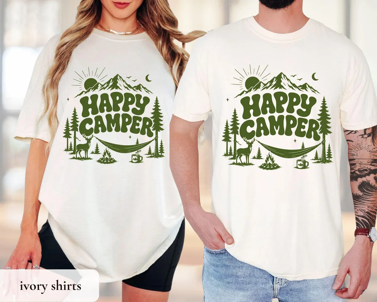 Couple in Ivory Comfort Colors tees, green happy camper lettering with a mountain, deer, hammock and campfire