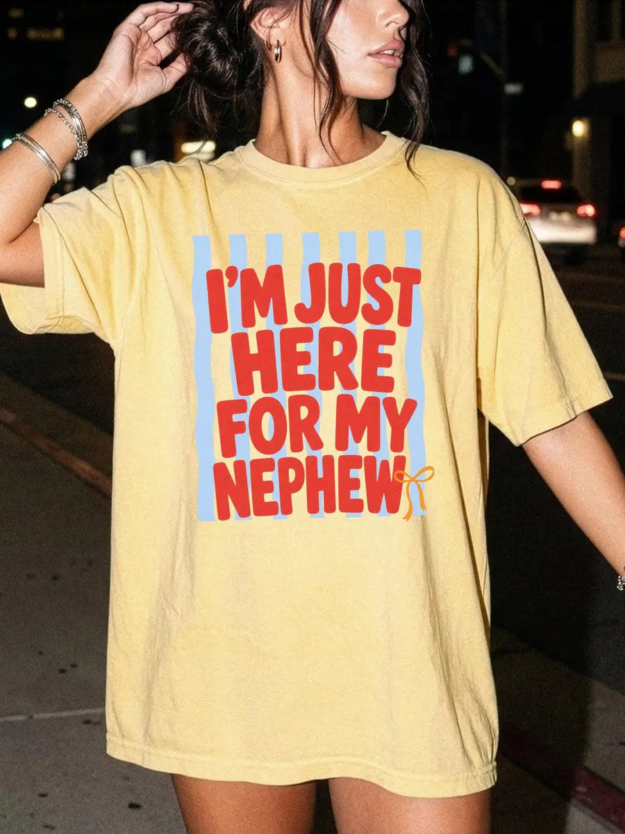 Woman in a Butter yellow Comfort Colors tee with bold red I'm just here for my nephew lettering and a small gold bow