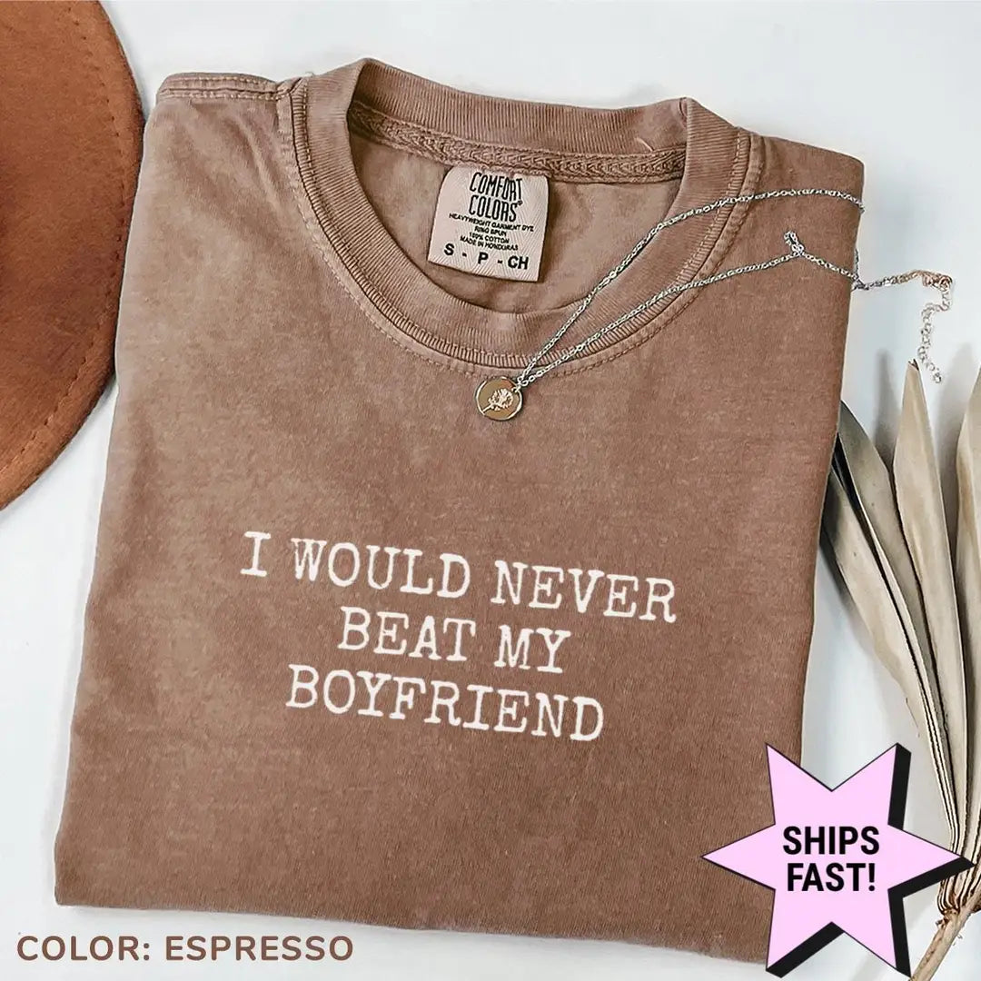Folded Espresso brown Comfort Colors tee with the three-line never beat my boyfriend text in light typewriter capitals