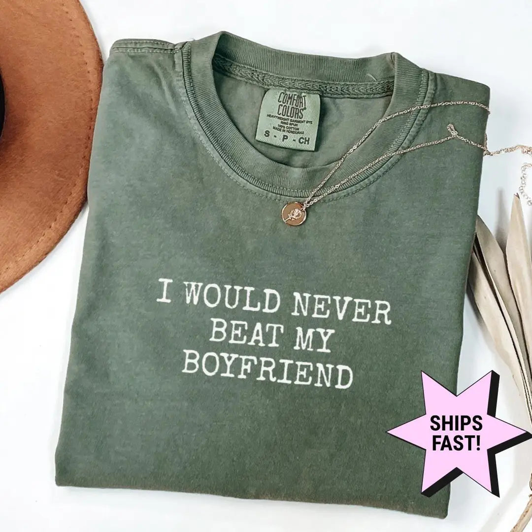 Folded Moss green Comfort Colors tee with the stacked never beat my boyfriend text in white typewriter letters