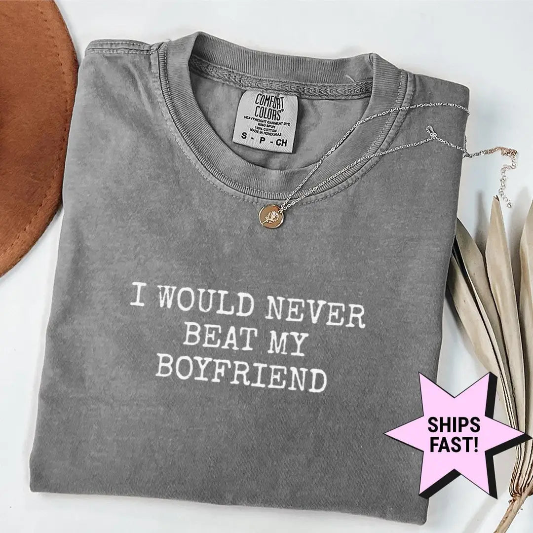Folded Pepper Comfort Colors tee with I WOULD NEVER BEAT MY BOYFRIEND in white typewriter capitals, hat and palm leaves