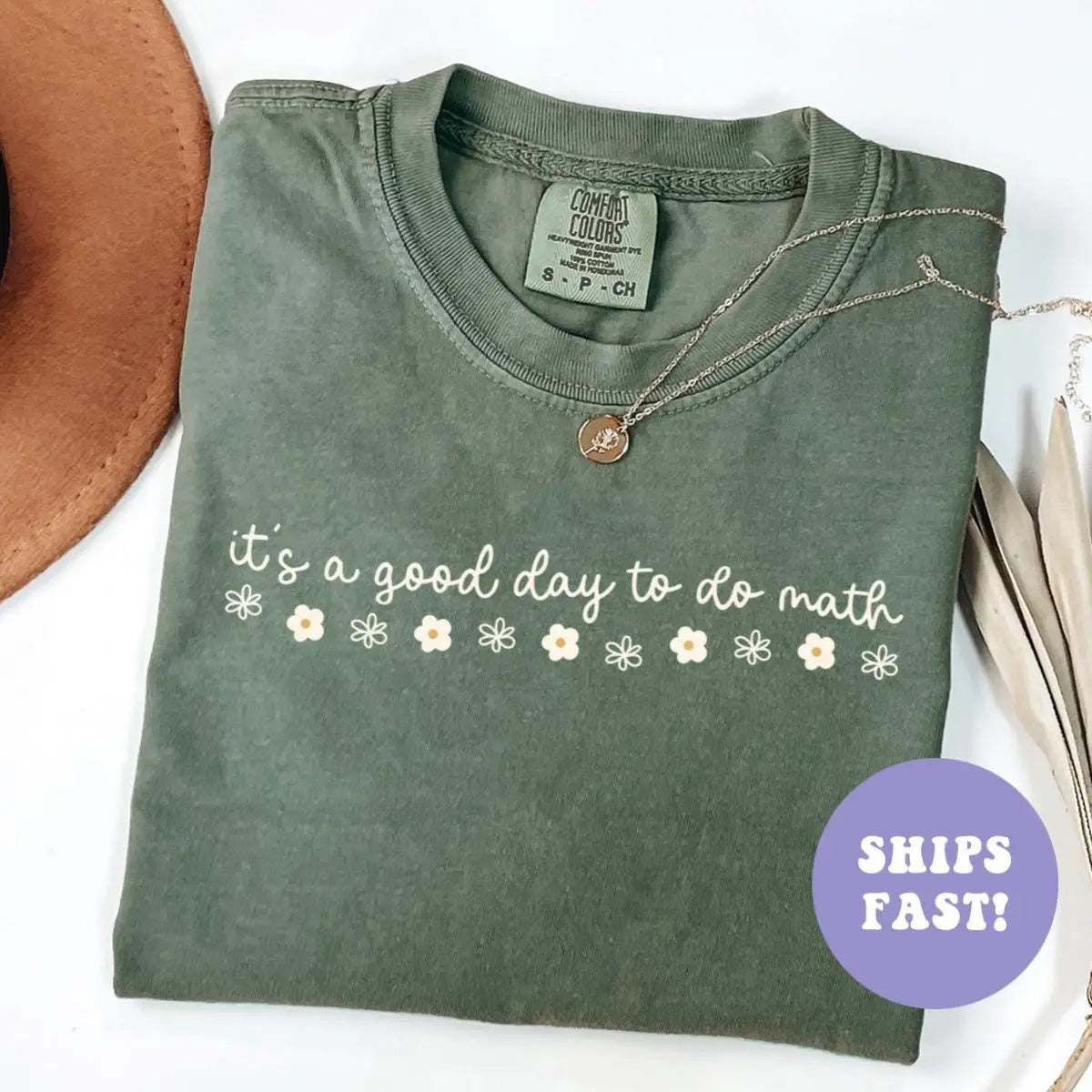 Folded Moss green Comfort Colors tee with it's a good day to do math in white cursive over small daisies