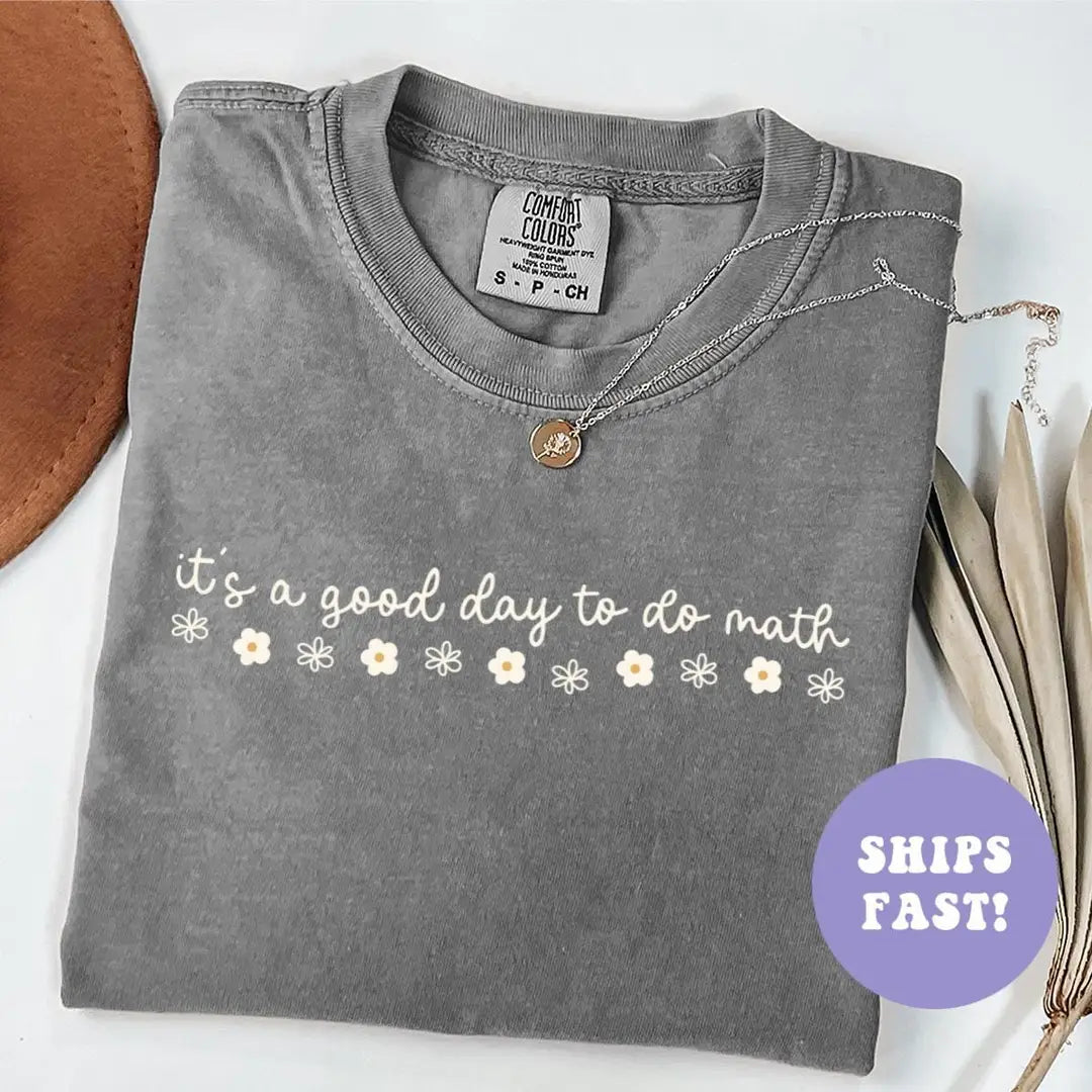 Folded Pepper Comfort Colors tee with it's a good day to do math in white cursive above a row of tiny daisies