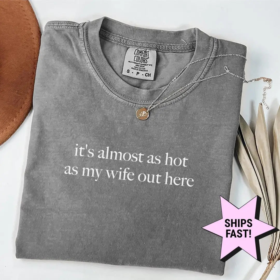 Folded Pepper Comfort Colors tee with it's almost as hot as my wife out here in white serif type, a necklace on the collar