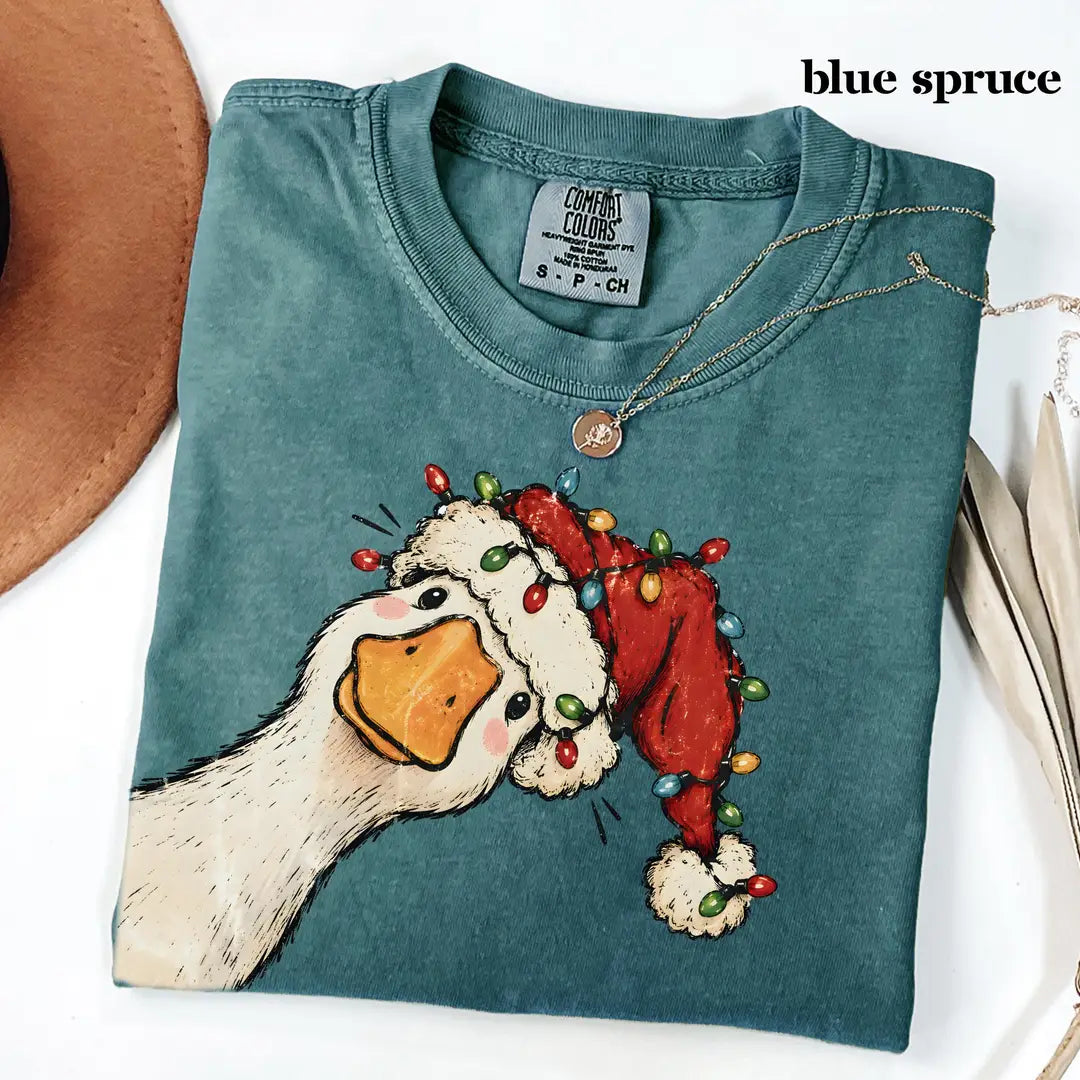 Folded Blue Spruce Comfort Colors tee in deep teal with the Santa hat goose and colorful string lights