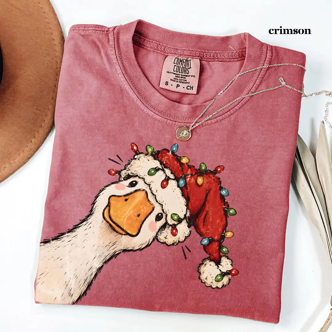 Folded Crimson red Comfort Colors tee with a goose in a Santa hat, the red hat blending into the soft red shirt