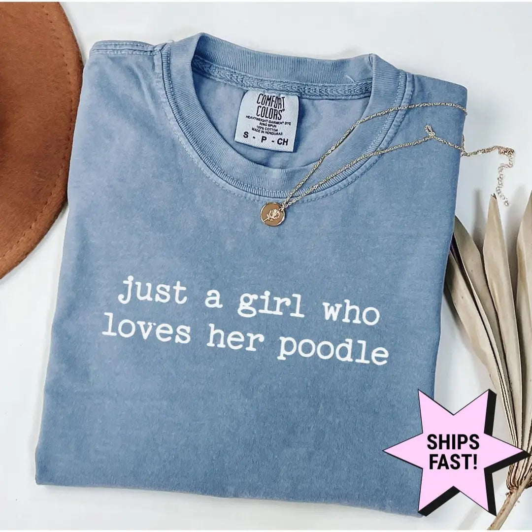 Folded Blue Jean Comfort Colors tee with just a girl who loves her poodle in white lowercase type, necklace at the collar