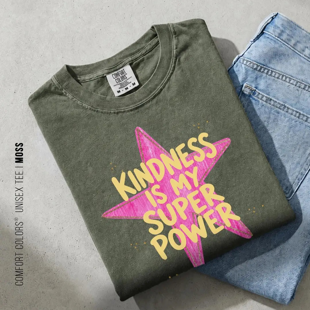 Folded Moss green Comfort Colors tee on blue jeans with yellow kindness is my super power over a pink brush star