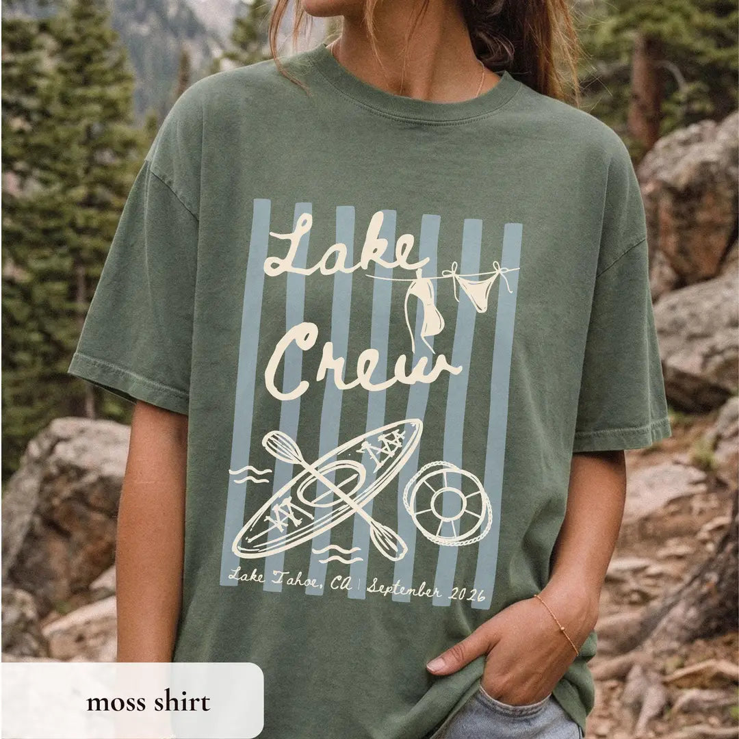 Woman in a Moss green Comfort Colors tee among rocks, ivory lake crew script with bikini clothesline, kayak and life ring
