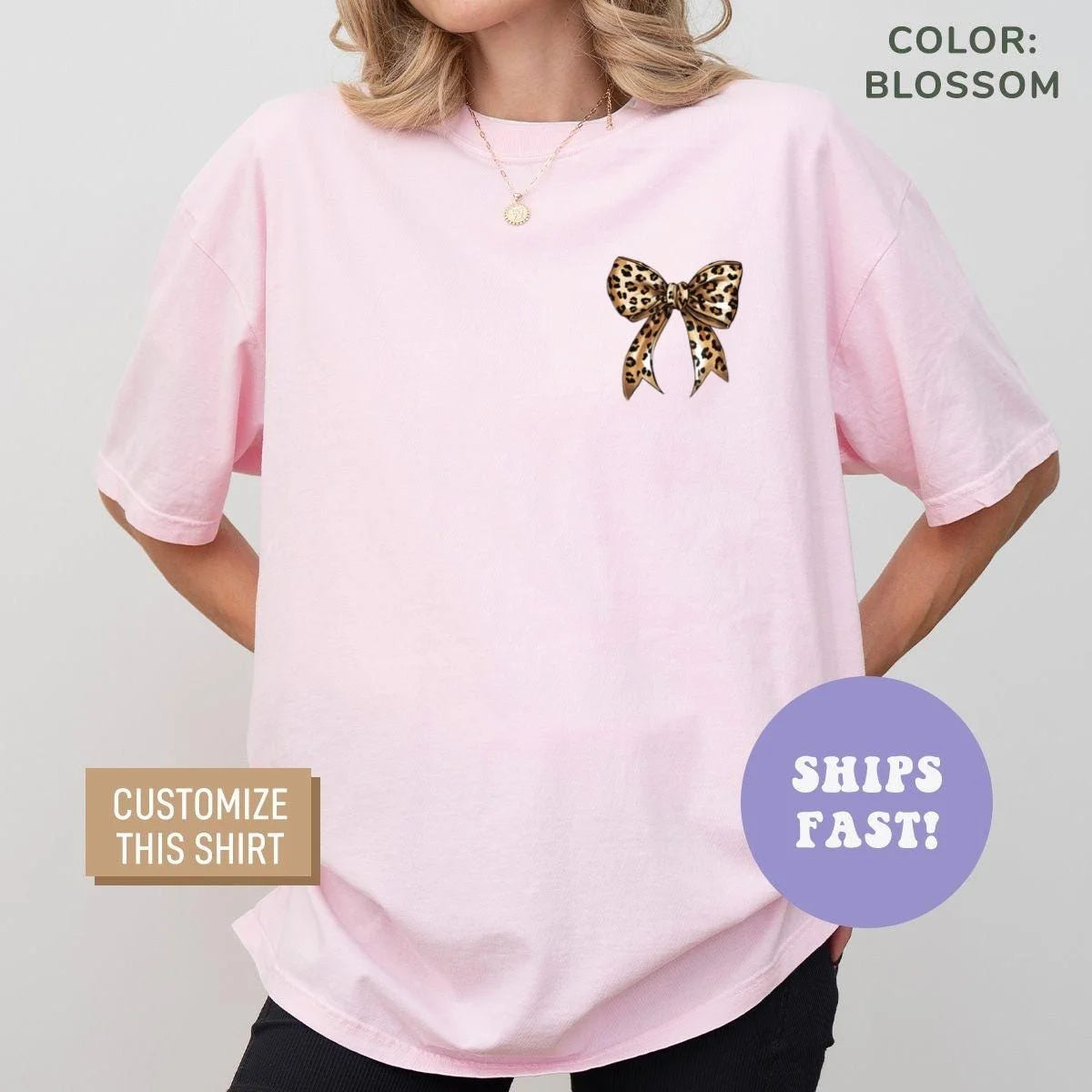 Woman in a Blossom pink Comfort Colors tee with a small leopard bow at the left chest and a gold pendant necklace