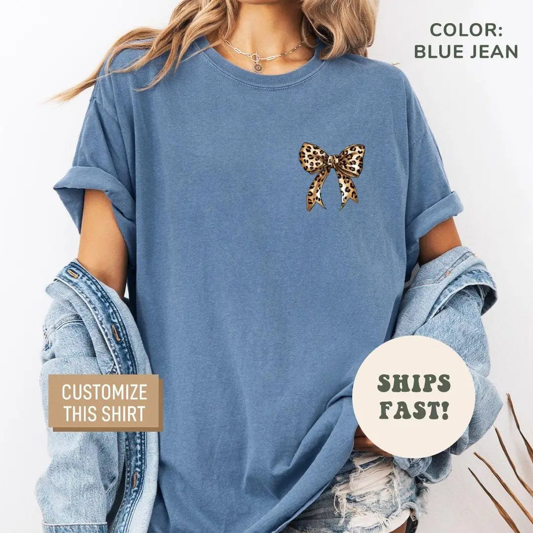 Woman in a Blue Jean Comfort Colors tee under a denim jacket, leopard print bow on the left chest