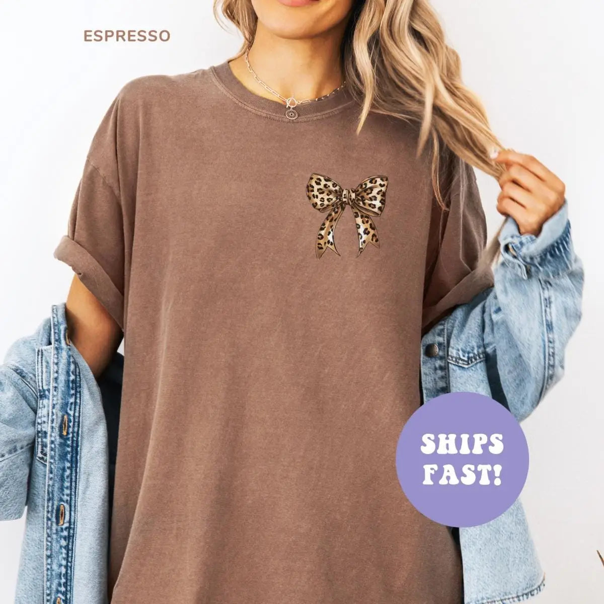 Woman in an Espresso Comfort Colors tee with a denim jacket over one arm, leopard print bow on the left chest