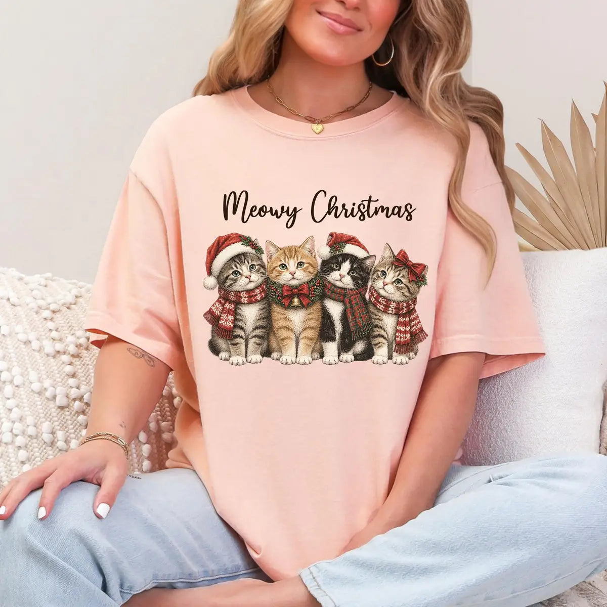 Woman in a Peachy Comfort Colors tee sitting on a couch, a small meowy christmas print of four kittens in santa hats