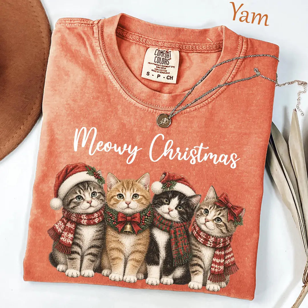 Folded Yam orange Comfort Colors tee with white meowy christmas script over four kittens in santa hats and plaid scarves