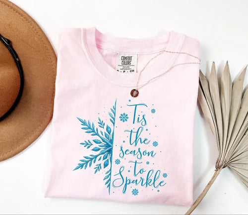 Blossom pink Comfort Colors T-shirt with blue 'Tis the Season to Sparkle lettering and snowflakes.