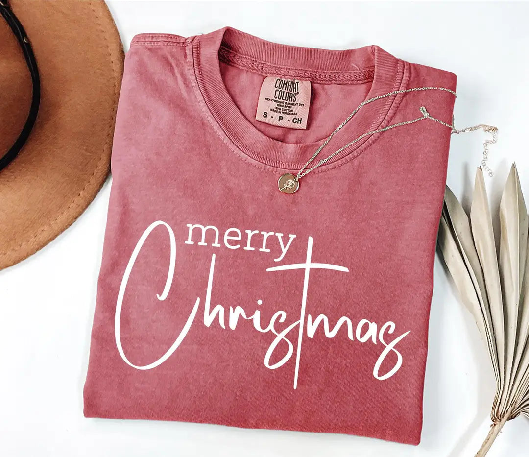 Merry Christmas typography on a folded faded Crimson Comfort Colors T-shirt.