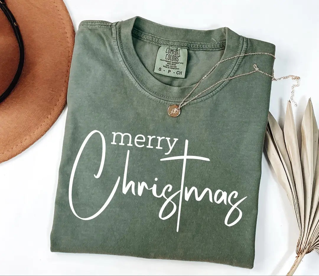 Merry Christmas typography on a folded Moss Comfort Colors 1717 T-shirt.