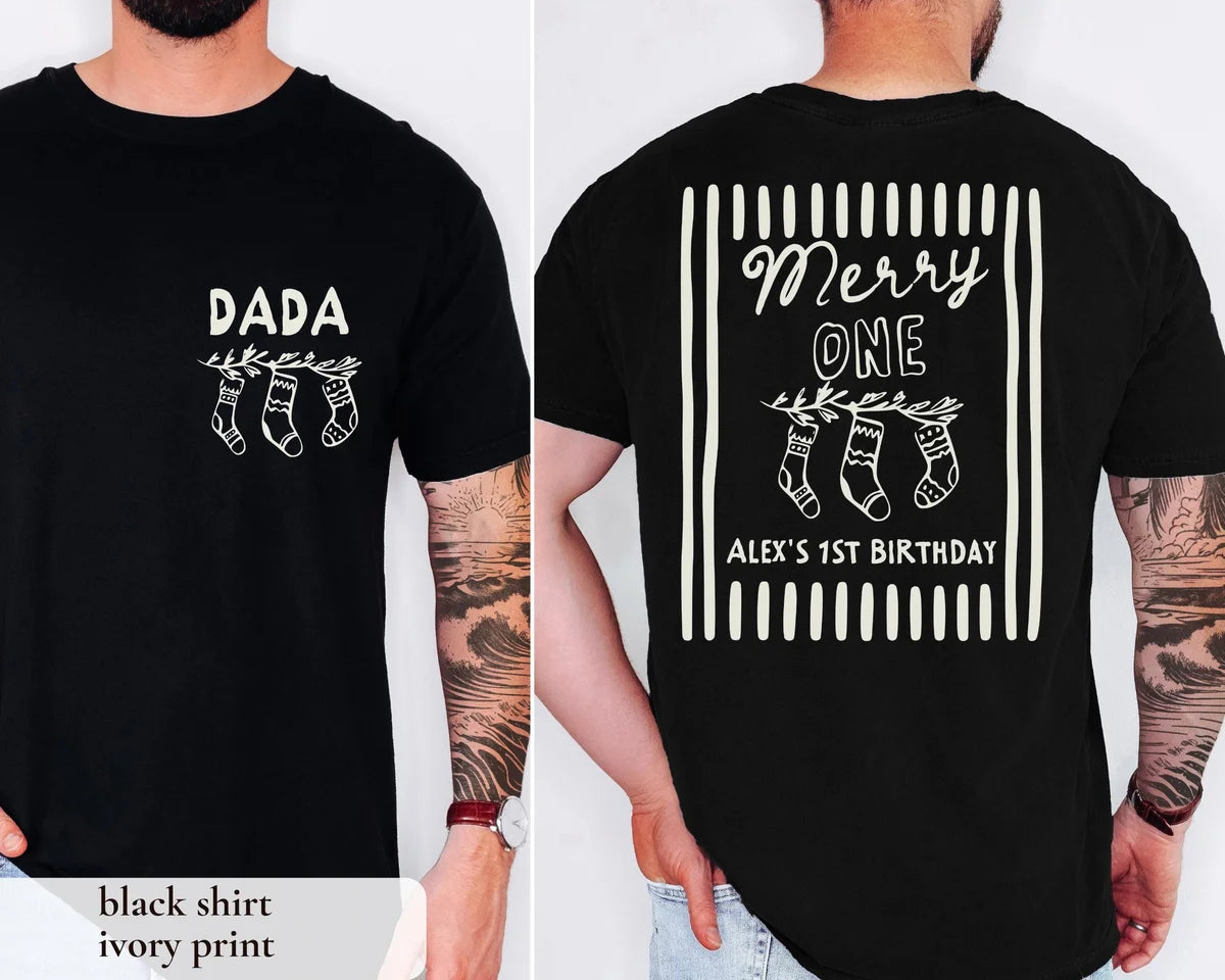 Man in a Black Comfort Colors tee, front with an ivory DADA stocking print and back with Merry ONE Alex's 1st Birthday