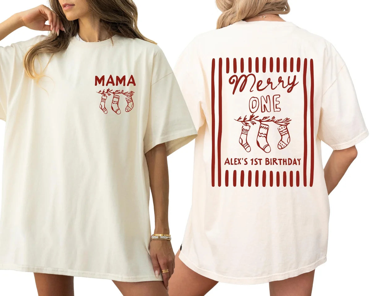 Woman in an Ivory oversized tee with a crimson MAMA stocking print, beside the back with Merry ONE and Alex's 1st Birthday