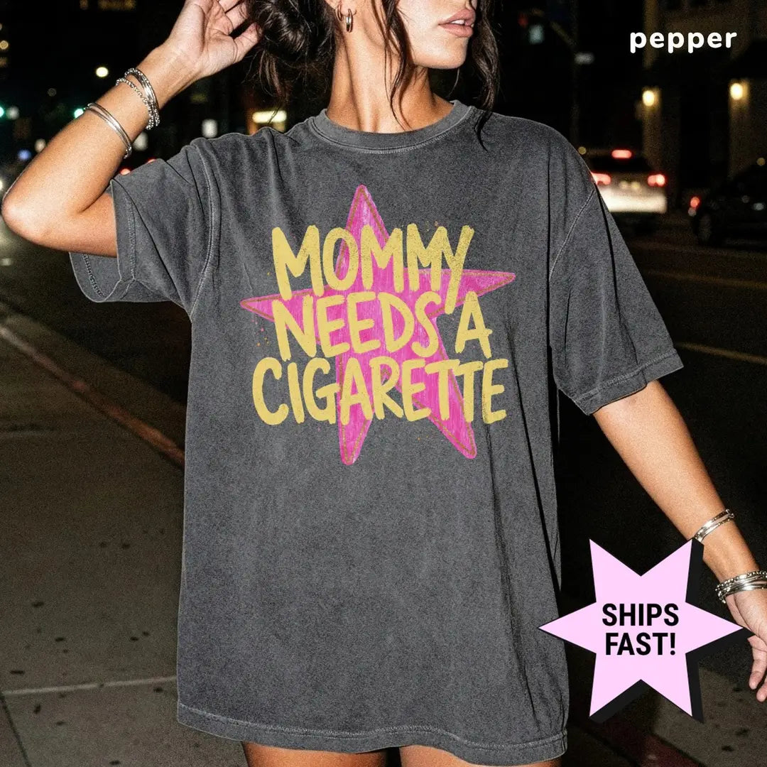 Woman in a Pepper Comfort Colors tee on a night street with yellow mommy needs a cigarette over a pink star