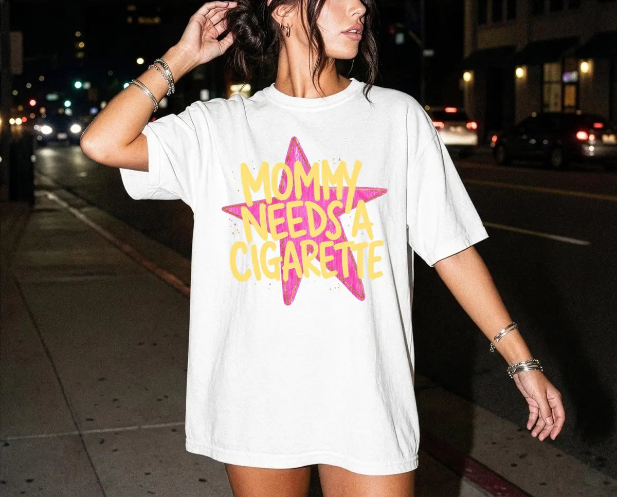 Woman in a White Comfort Colors tee on a night street, bracelets, with yellow mommy needs a cigarette on a star