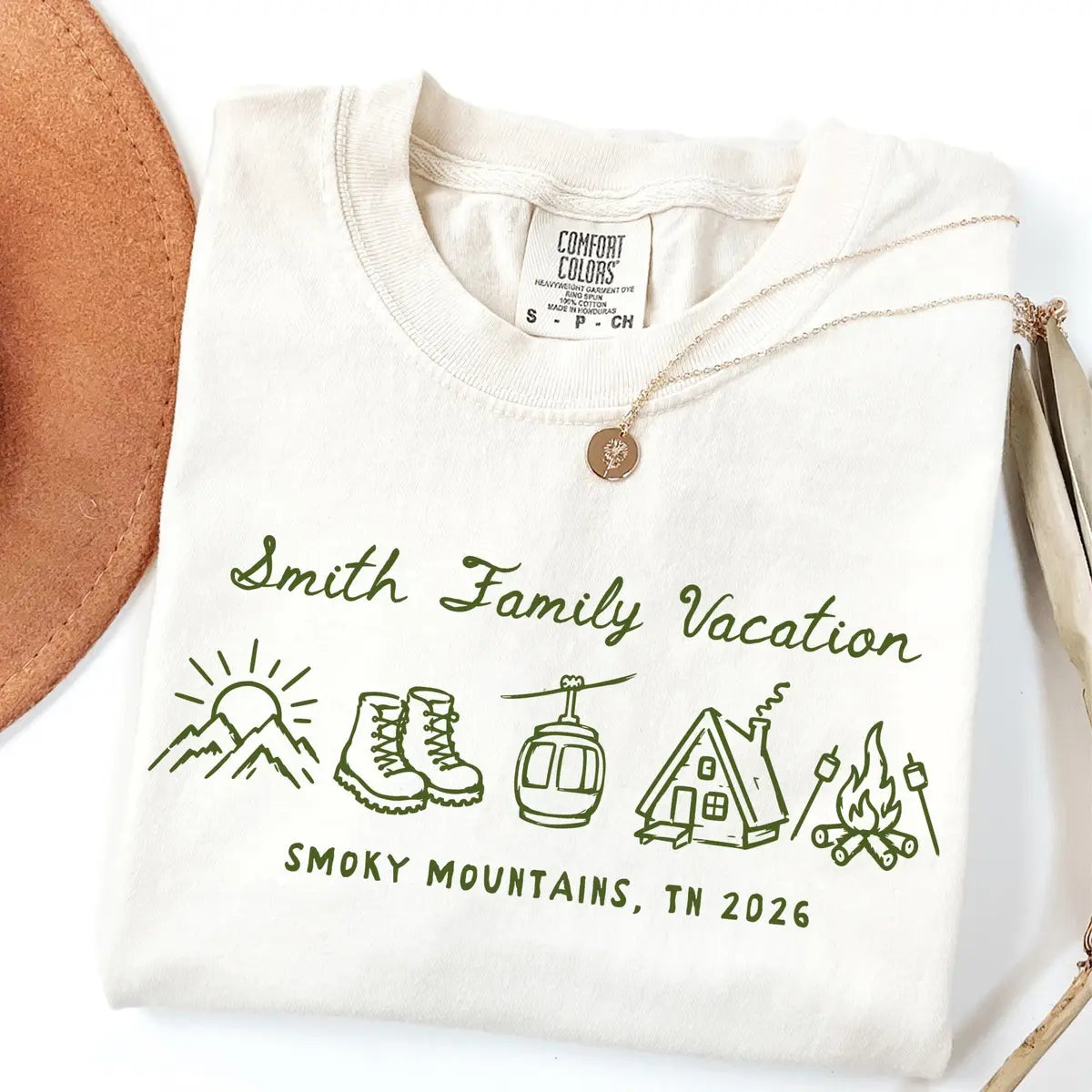Folded Ivory Comfort Colors tee with green Smith Family Vacation script, hiking boots, gondola, cabin and Smoky Mountains, TN