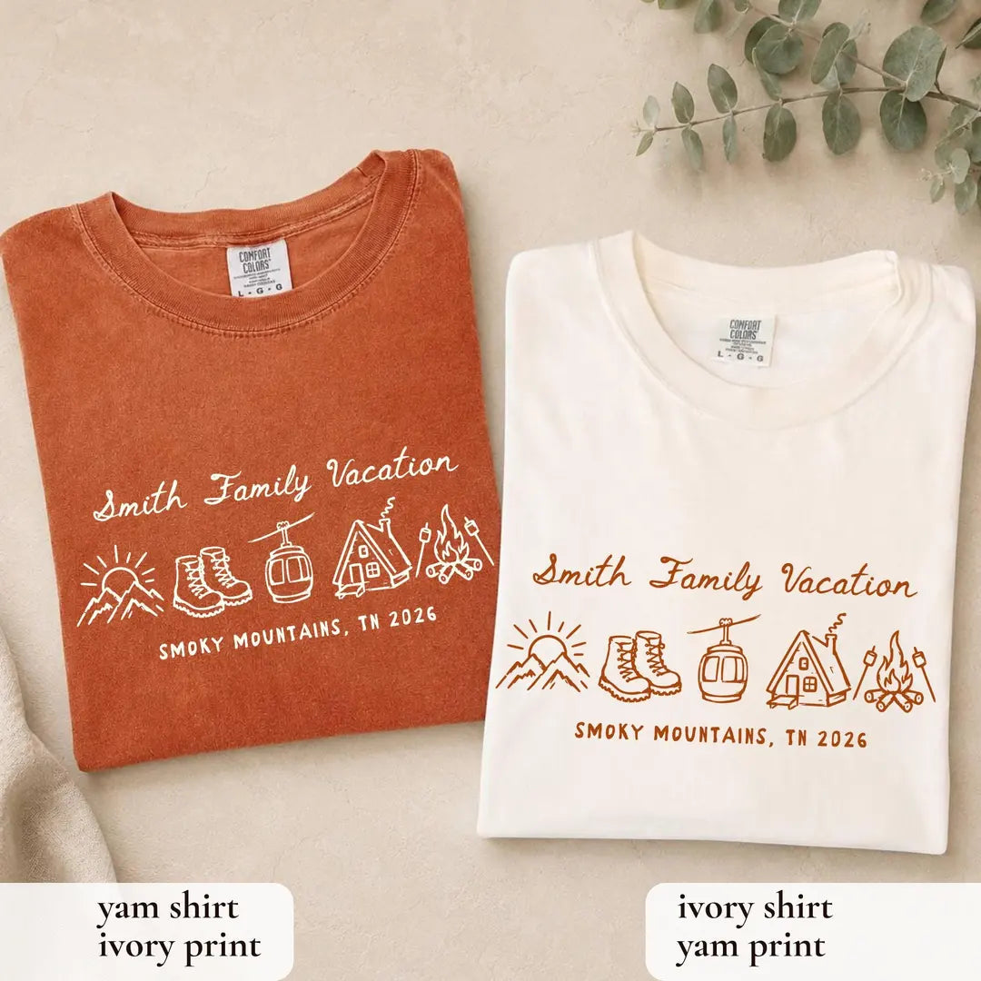 Folded Yam orange and Ivory Comfort Colors tees on a tan surface with Smith Family Vacation, boots, gondola and cabin