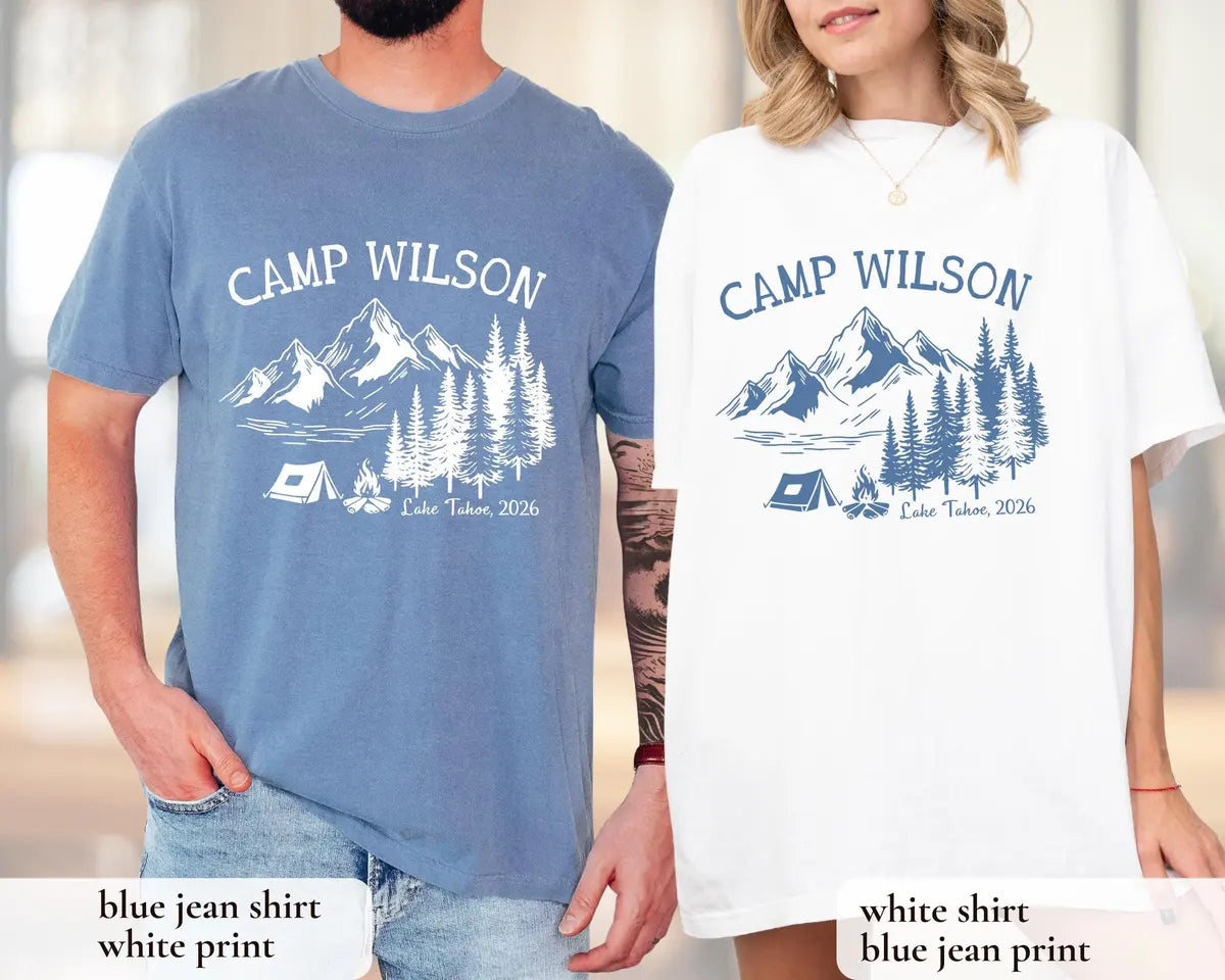 Man in a Blue Jean and woman in a White Comfort Colors tee, matching Camp Wilson mountain, pines and tent designs in blue