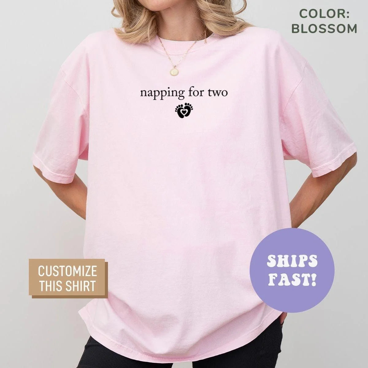 Woman in a Blossom pink Comfort Colors tee with napping for two and a small black baby feet heart on the chest