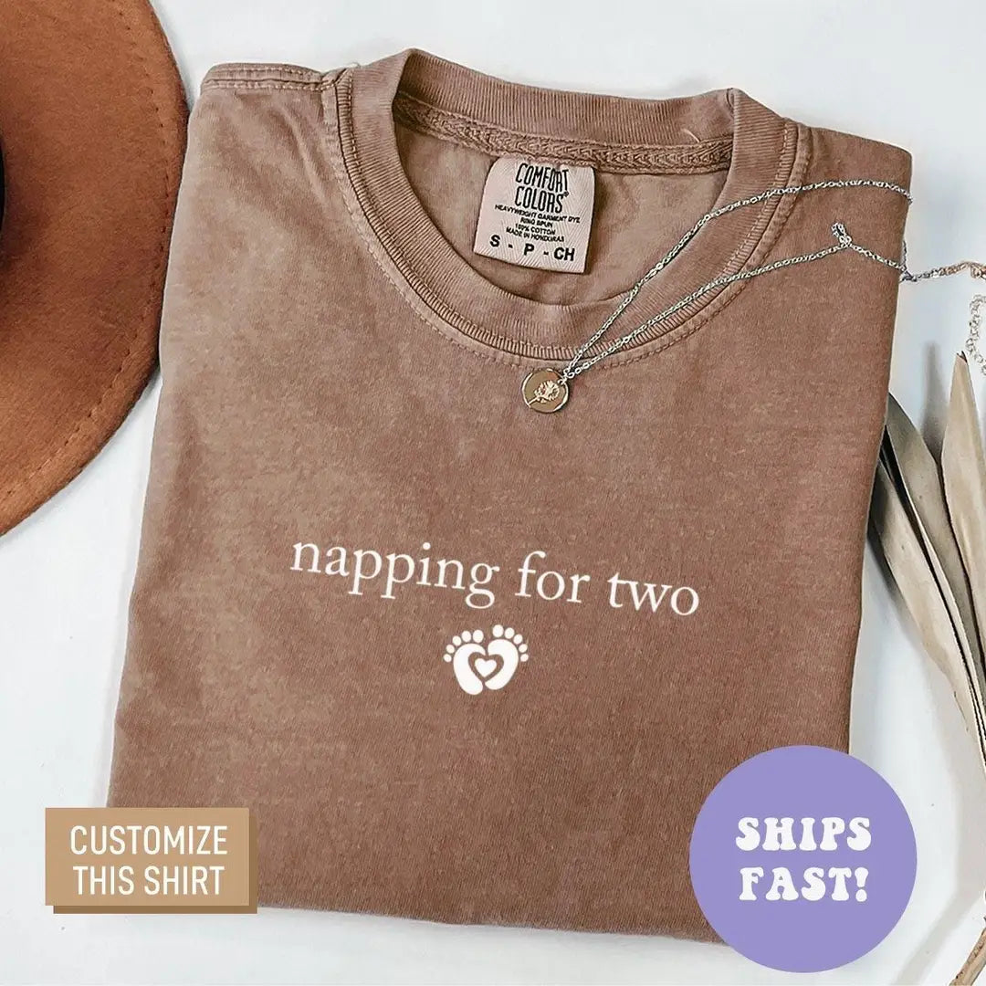 Folded Espresso brown Comfort Colors tee with napping for two and a baby feet heart printed in light serif and icon