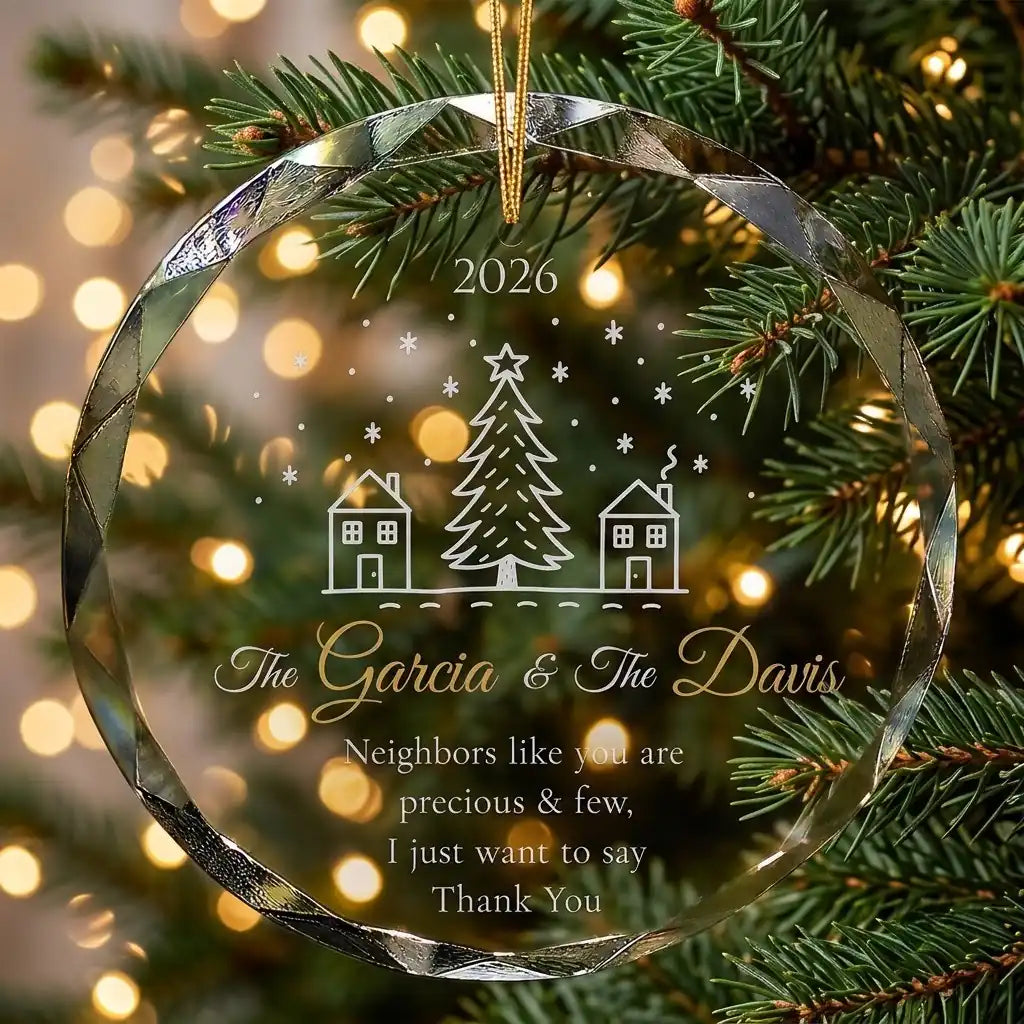 Personalized clear glass neighbor gift ornament displayed hanging on Christmas tree branch with warm sparkling holiday lights background