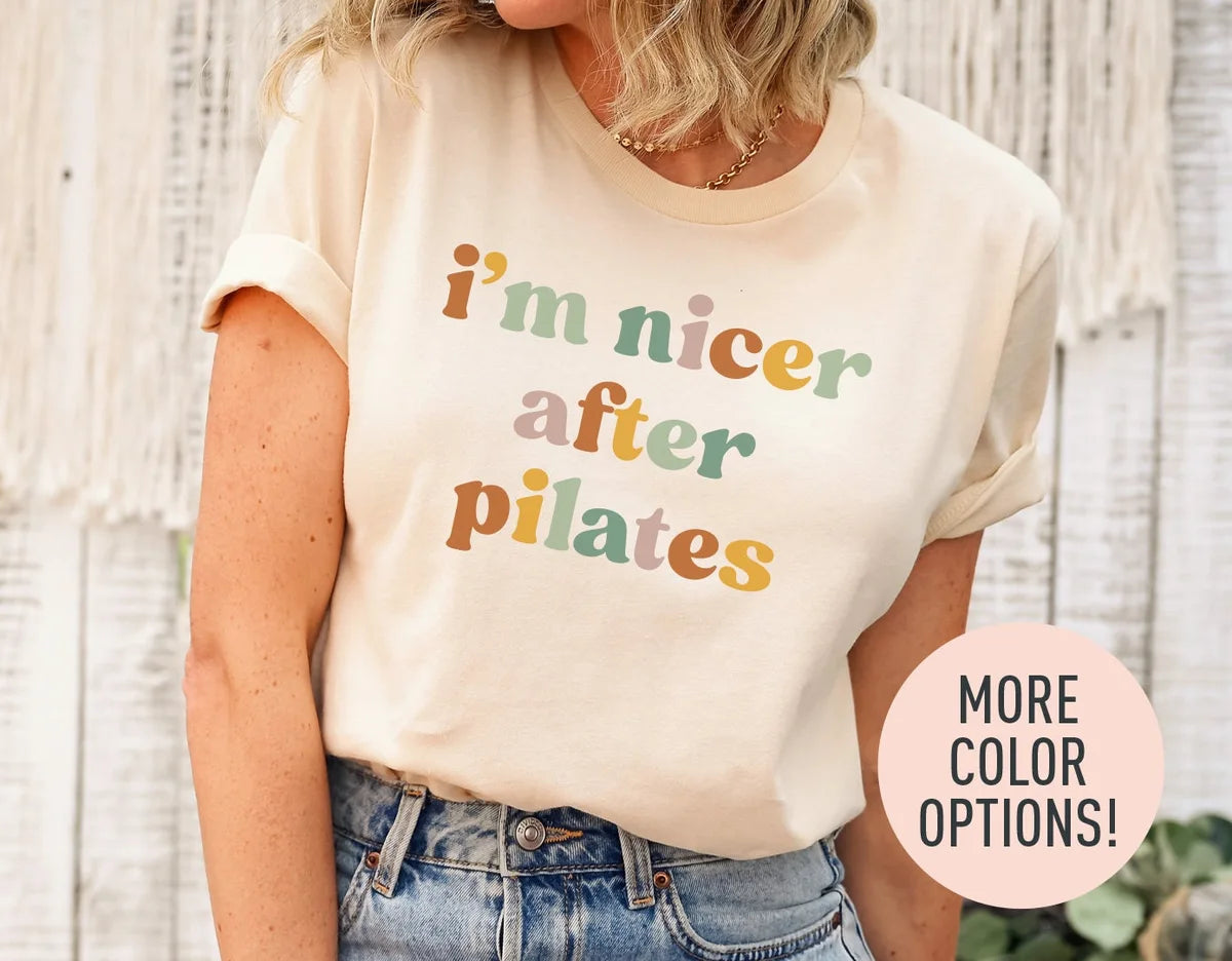 Woman in a natural cream tee with rolled sleeves and jeans, i'm nicer after pilates in sage, rose and rust retro type
