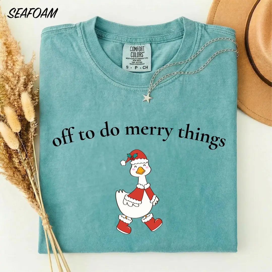 Seafoam Comfort Colors 1717 tee with 'Off to do merry things' print and a goose in a Christmas outfit.