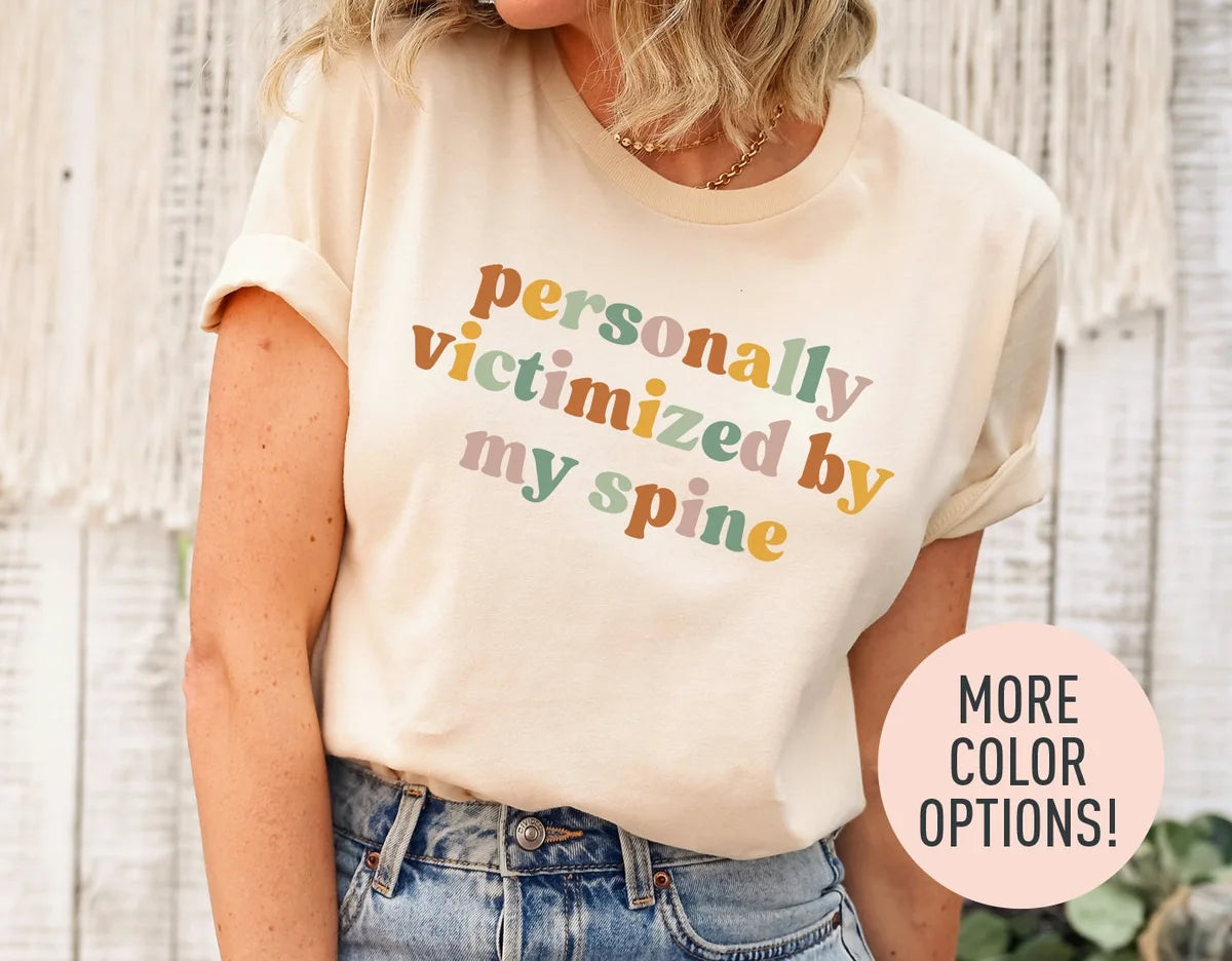 Woman in a natural cream tee with rolled sleeves and jeans, personally victimized by my spine in rust, sage and rose