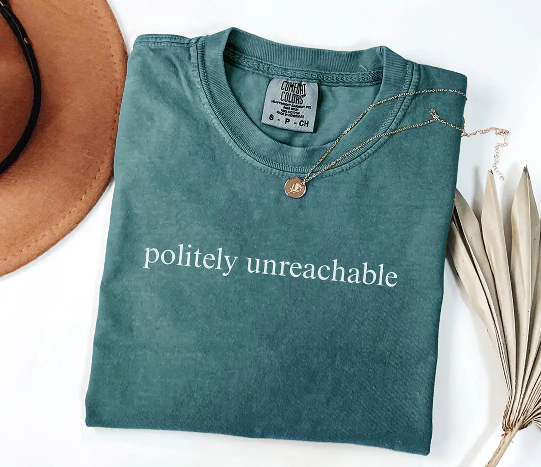 Blue Spruce Comfort Colors T-shirt with white 'politely unreachable' lettering, folded mockup.