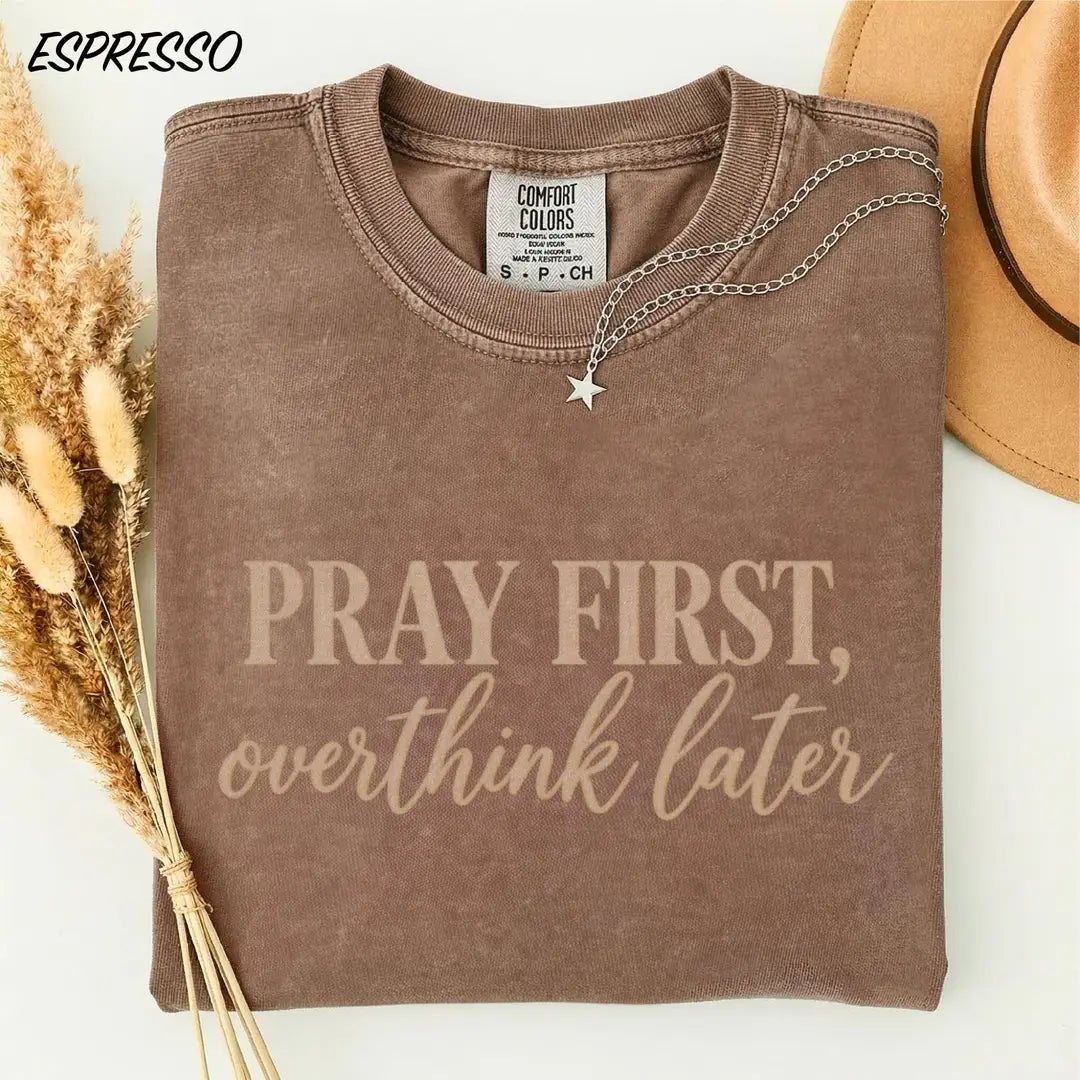 Espresso Comfort Colors 1717 tee with beige 'Pray first, overthink later' typography.