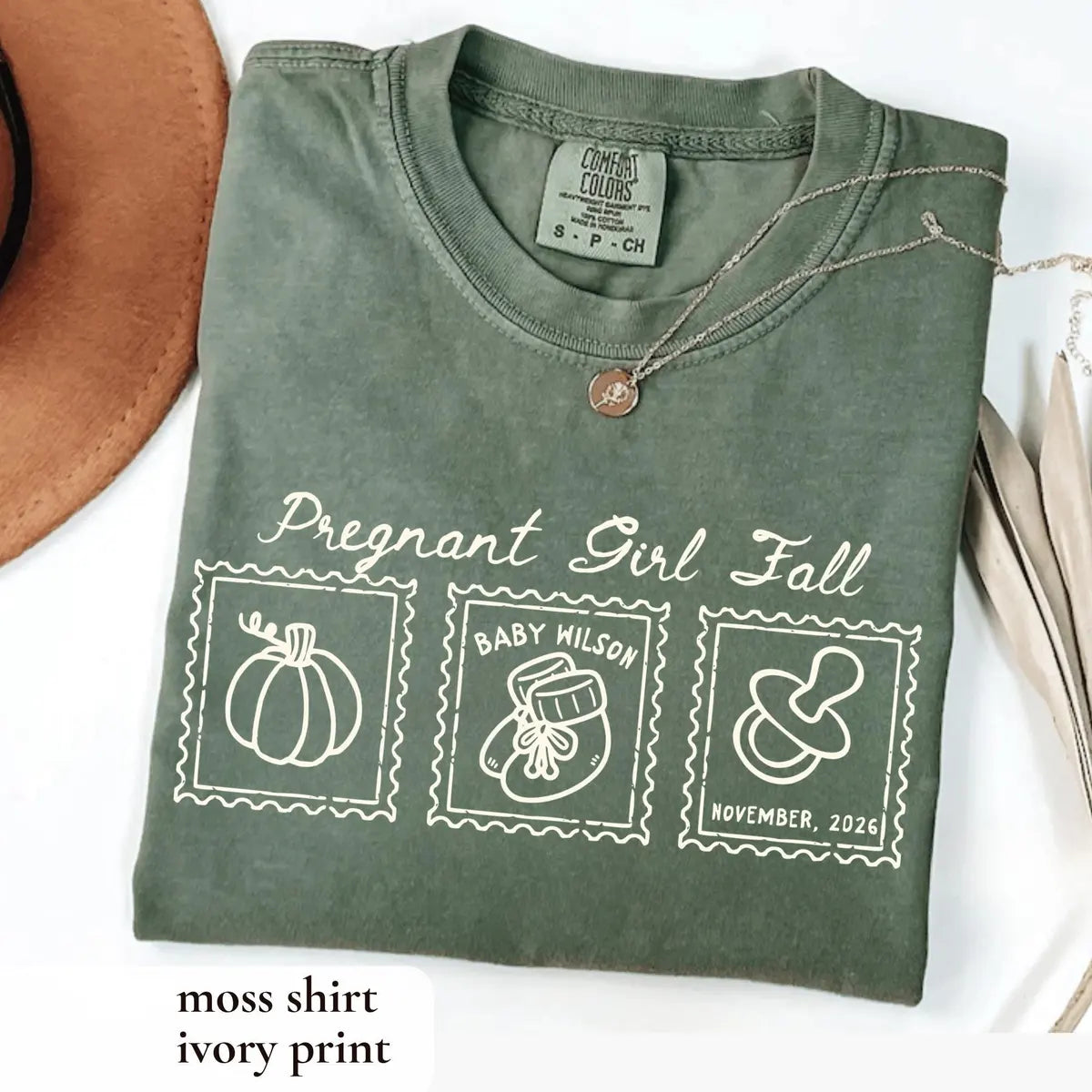 Folded Moss green Comfort Colors tee with ivory pregnant girl fall script above three outlined stamp frames
