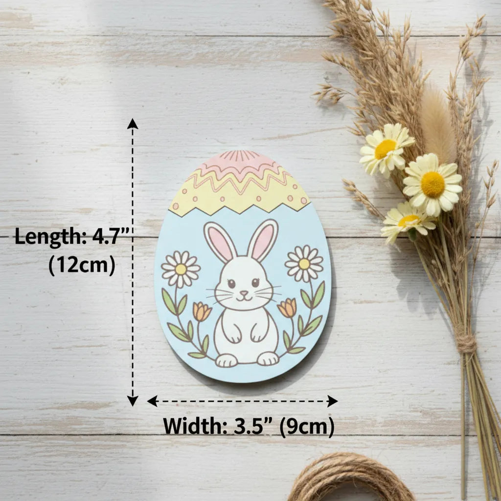 Decorative Easter egg with a rabbit design, flowers, and measurements on a wooden surface with dried flowers.