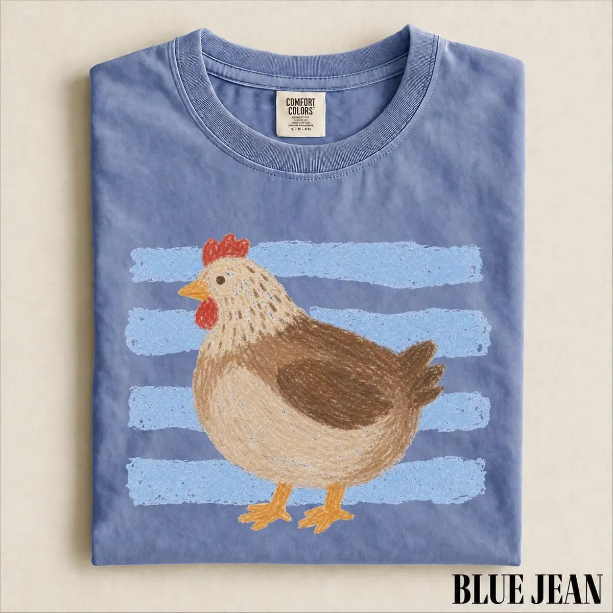 Folded Blue Jean Comfort Colors tee with a brown hen and orange feet over light blue crayon-style stripes