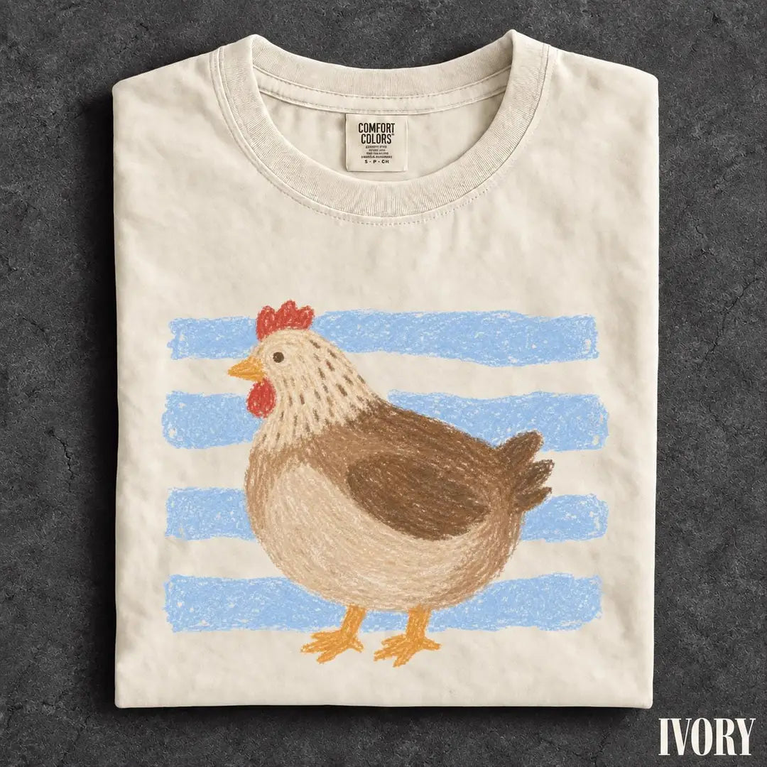 Folded Ivory Comfort Colors tee on dark stone with a brown hen and red comb over light blue brush stripes