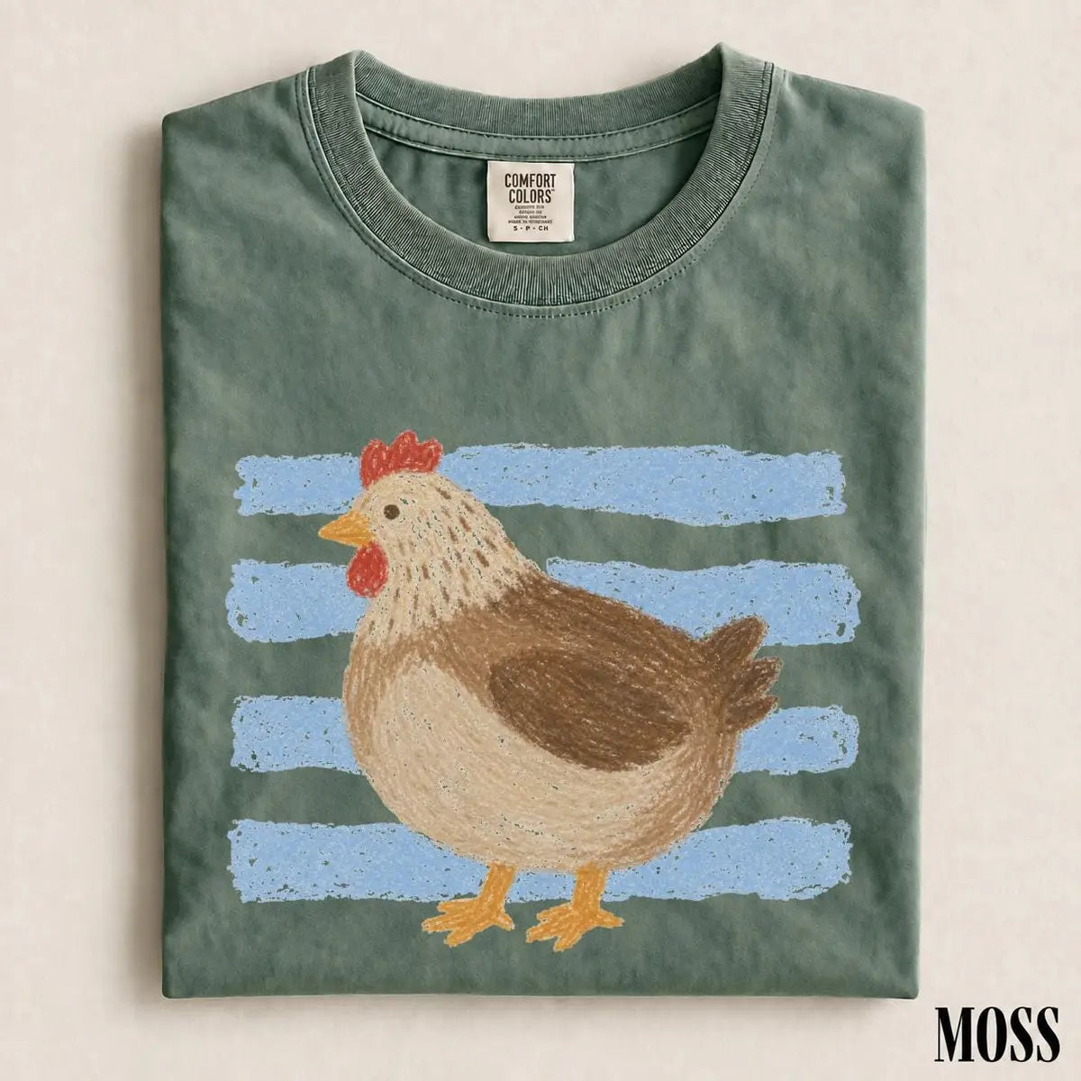Folded Moss green Comfort Colors tee with a large brown hen standing in front of pale blue brush stripes