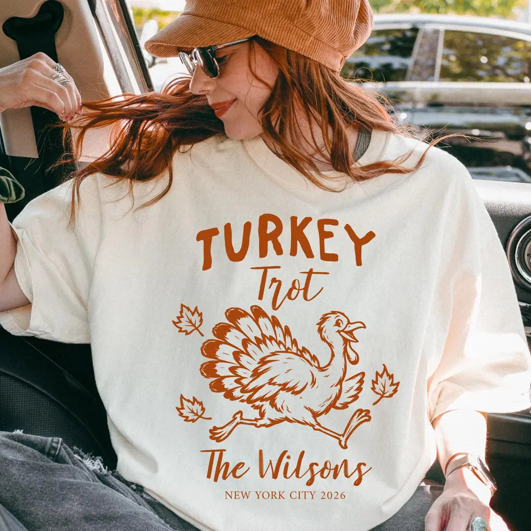 Woman in a tan cap and sunglasses in a car, Ivory Comfort Colors tee, rust Turkey Trot running turkey and The Wilsons